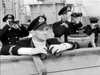 Four British naval convoy officers in uniform stand on the deck of a ship for The Cruel Sea (1953) DVD, three of them looking through binoculars out toward the sea.