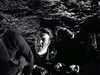 Two men struggle in turbulent, dark water in a scene from The Cruel Sea (1953) DVD.