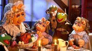 Miss Piggy, Kermit, and friends share a festive meal by candlelight in a cozy setting inspired by The Muppet Christmas Carol, as seen in The Muppet Christmas Carol DVD (1992).